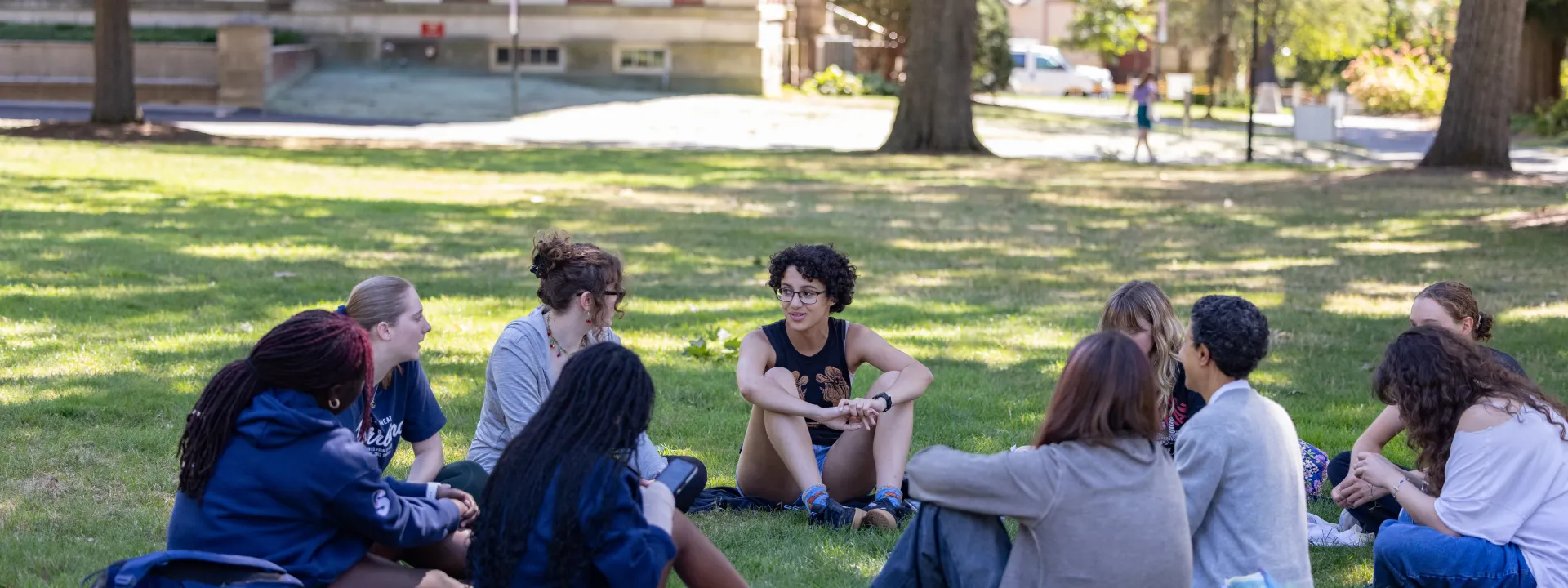 Students sit outside in a circle discussing a reading
