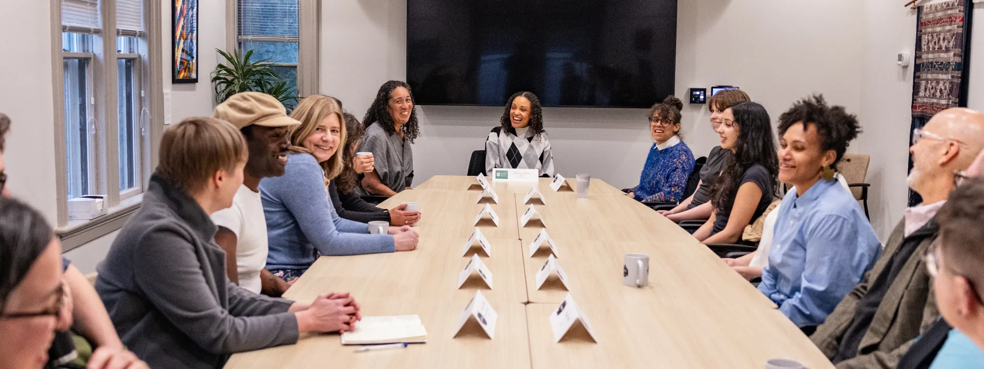 Faculty and staff members laugh around a table at the Kahn Institute