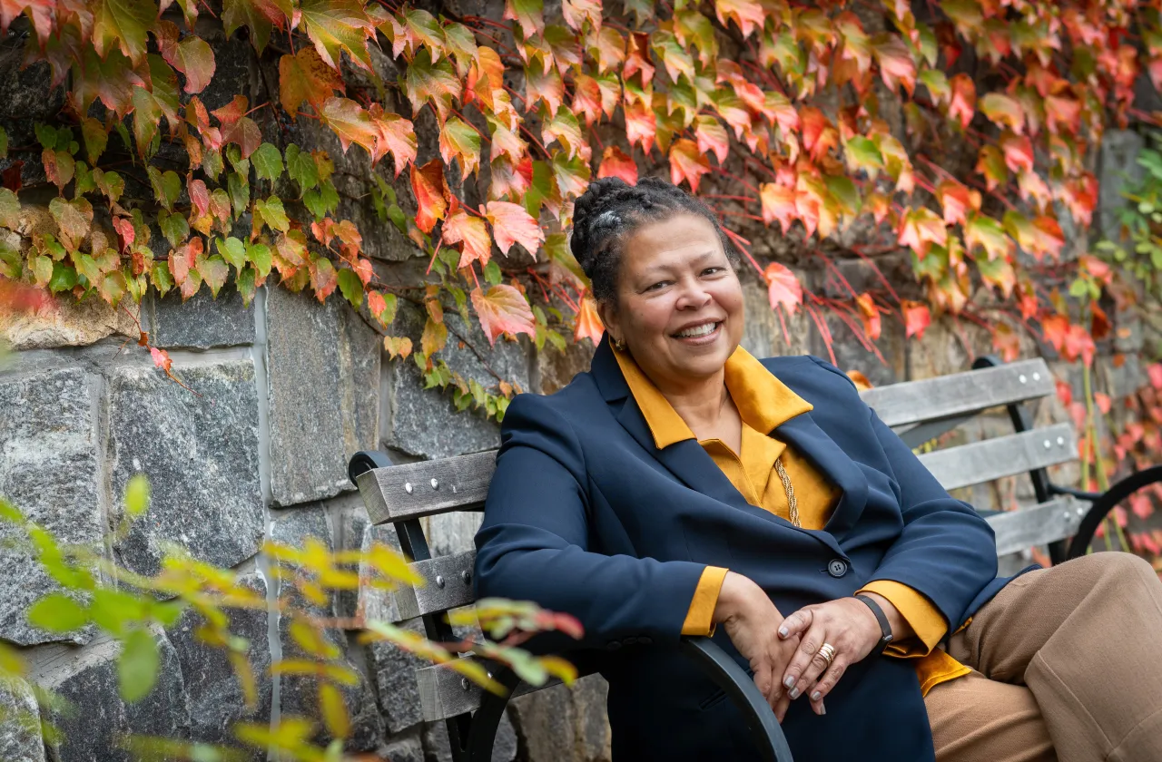 Sarah Willie-LeBreton smiling outdoors and sitting on a bench.