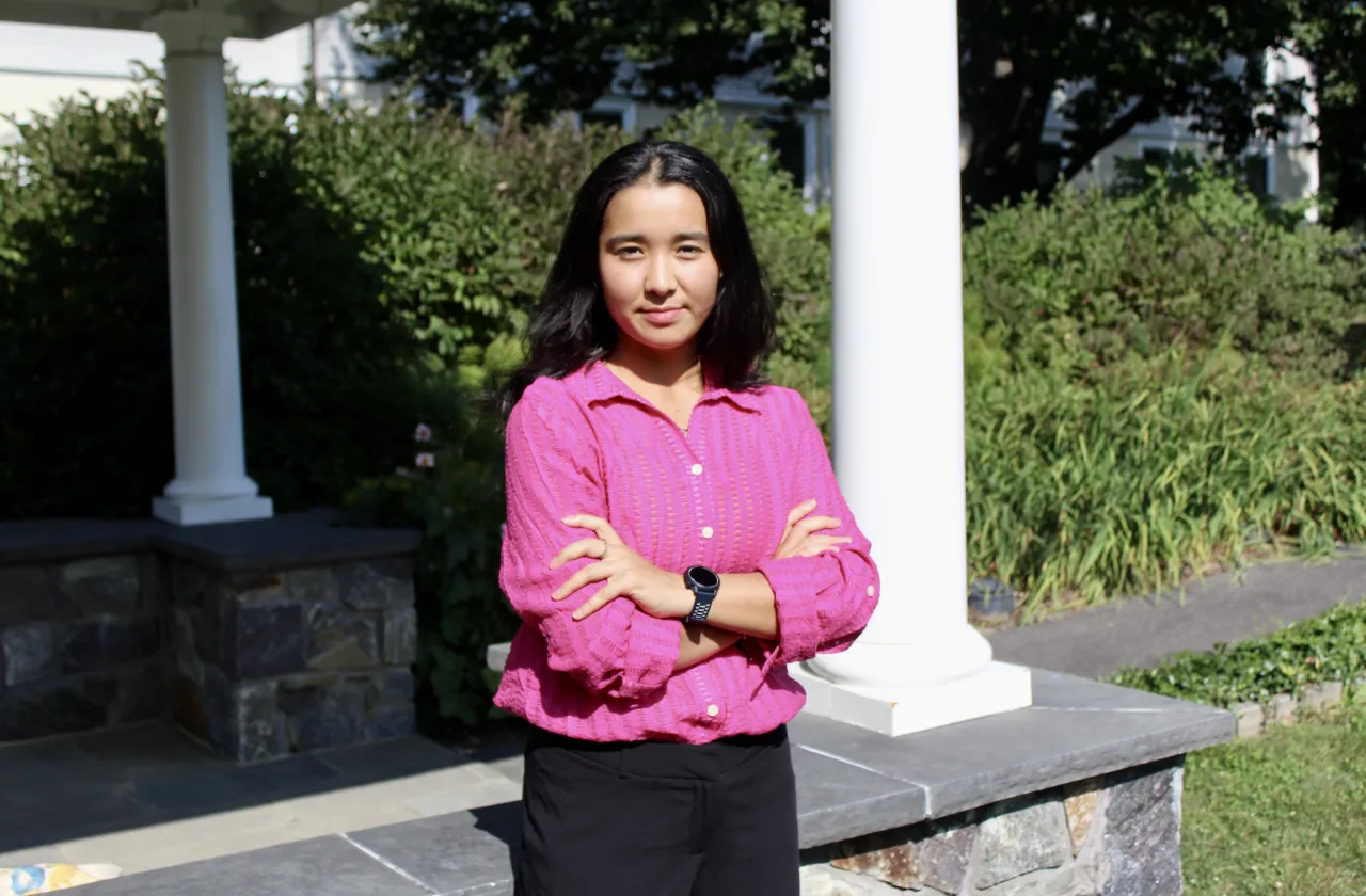 Nadira Talayee wears a pink top and looks at the camera with crossed arms. Portrait by Brooke Chandler ’25
