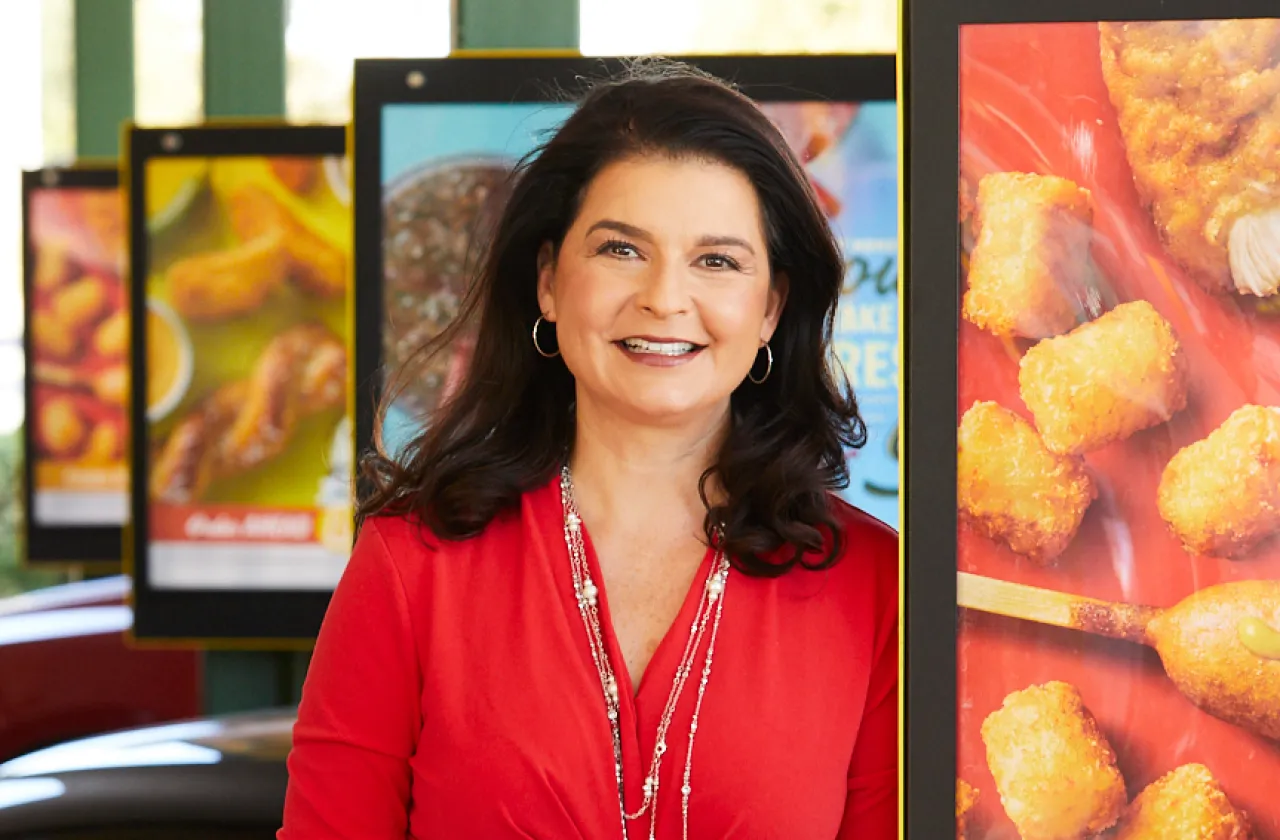 Claudia San Pedro smiling by the menus at a Sonic restaurant