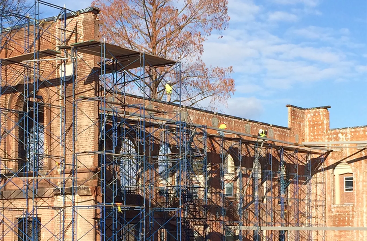 Construction workers on scaffolding around Neilson wall