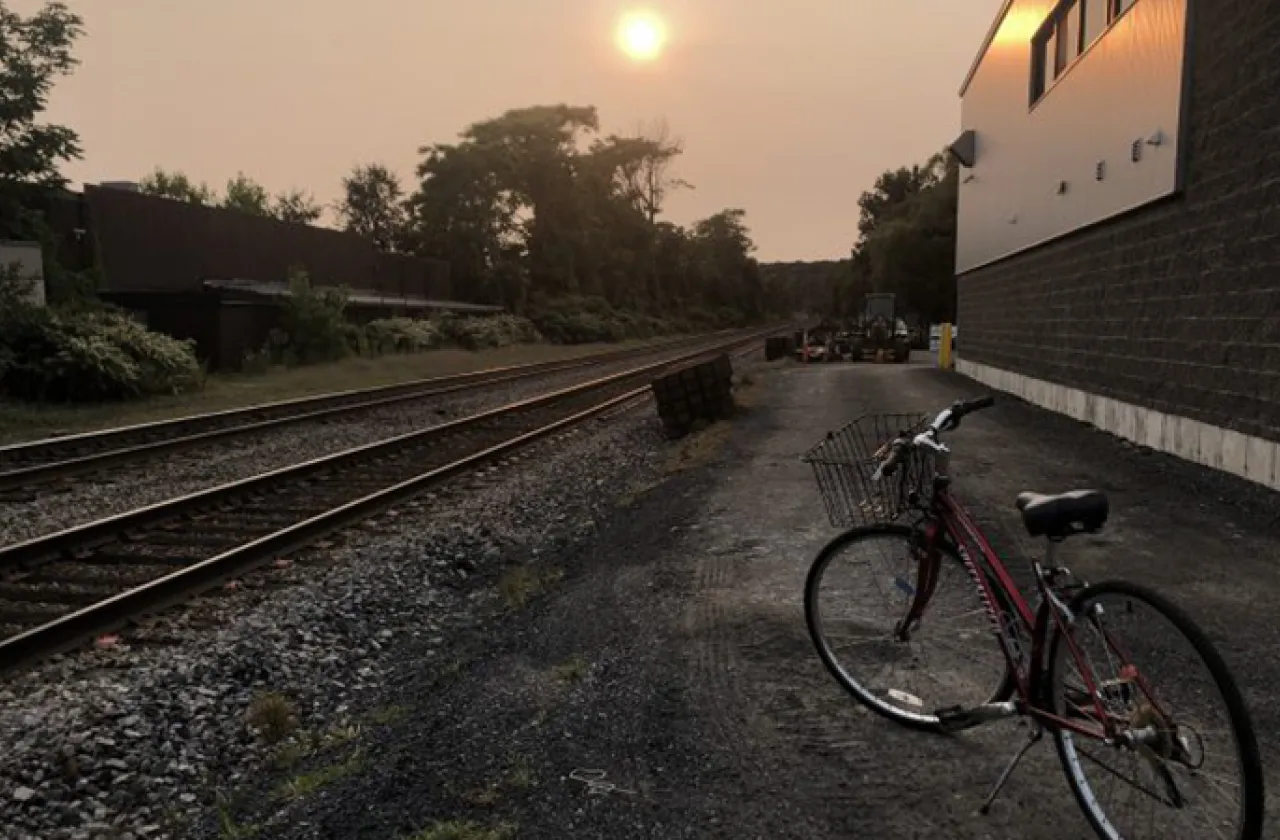 Bicycle near train tracks with sun setting by Liliana Wollheim Martinez