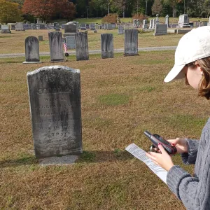 A student holds a tracking device in a cemetery.