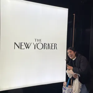 Abril in front of a sign for the New Yorker