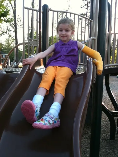 Arden Grim as a young child with a bright yellow cast on her left arm.