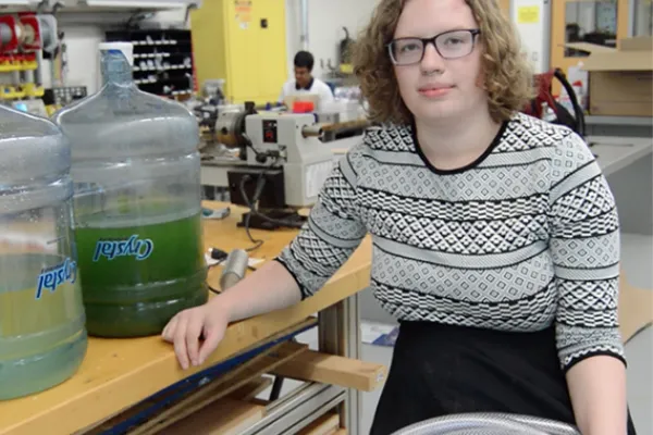 Max Pabilionia in a science lab with 5 gallon buckets of algae