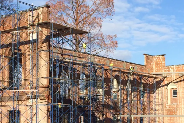 Construction workers on scaffolding around Neilson wall