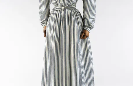 A long-sleeved, floor-length, grey and white striped dress.