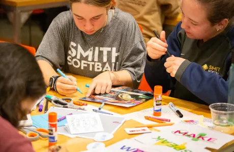 Two students lean over a table with markers while creating a zine at ZineFest