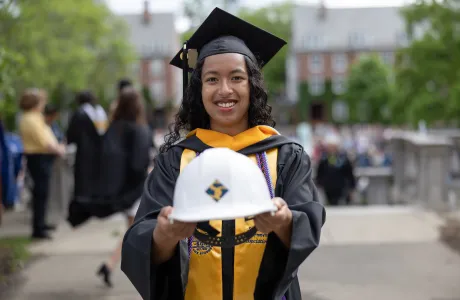 An engineering graduate holds out her Smith hard hat to the camera on Commencement Day
