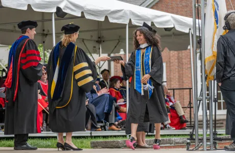 A graduate walks across the stage during Commencement