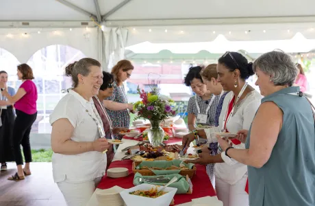 Alums smile and talk over food during Reunion. A beautiful bouquet of flowers adorns the center of the table.