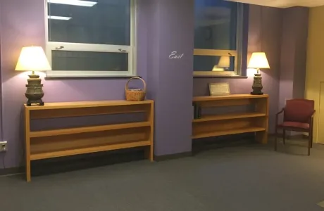 A room with purple walls, soft lighting, and directions noted on the walls.