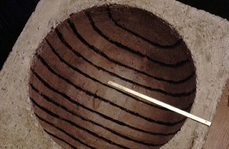 A concrete block with a circular cutout featuring parallel dark lines across its surface