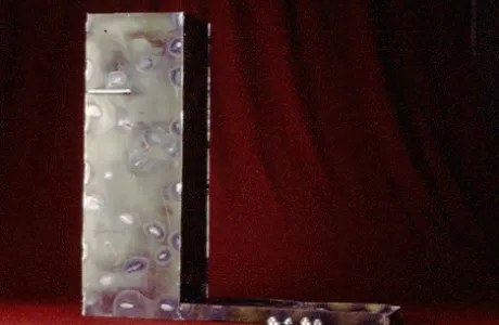 A tall, abstract metal sculpture with three small metallic balls at its base