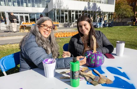 A Smithie and a family member paint a pumpkin on Chapin lawn during Family Weekend.