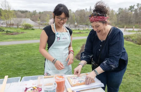 A student looks on as a community member makes paper