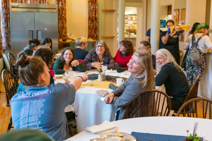 A group of attendees at lunch talk and smile around their table.