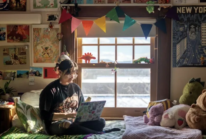 Cloud Osmond sitting on a bed, working on a laptop.