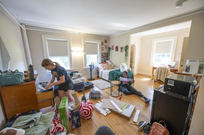 Two students organize their room and put furniture together.