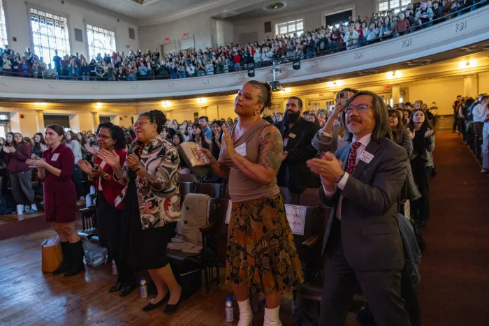 President Sarah Willie-LeBreton and others stand and clap in the auditorium.