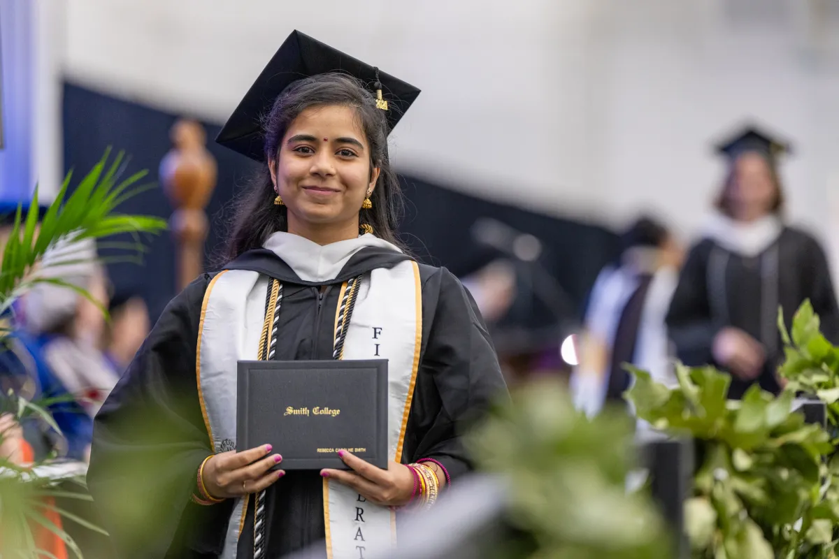 A student holding a diploma at Commencement