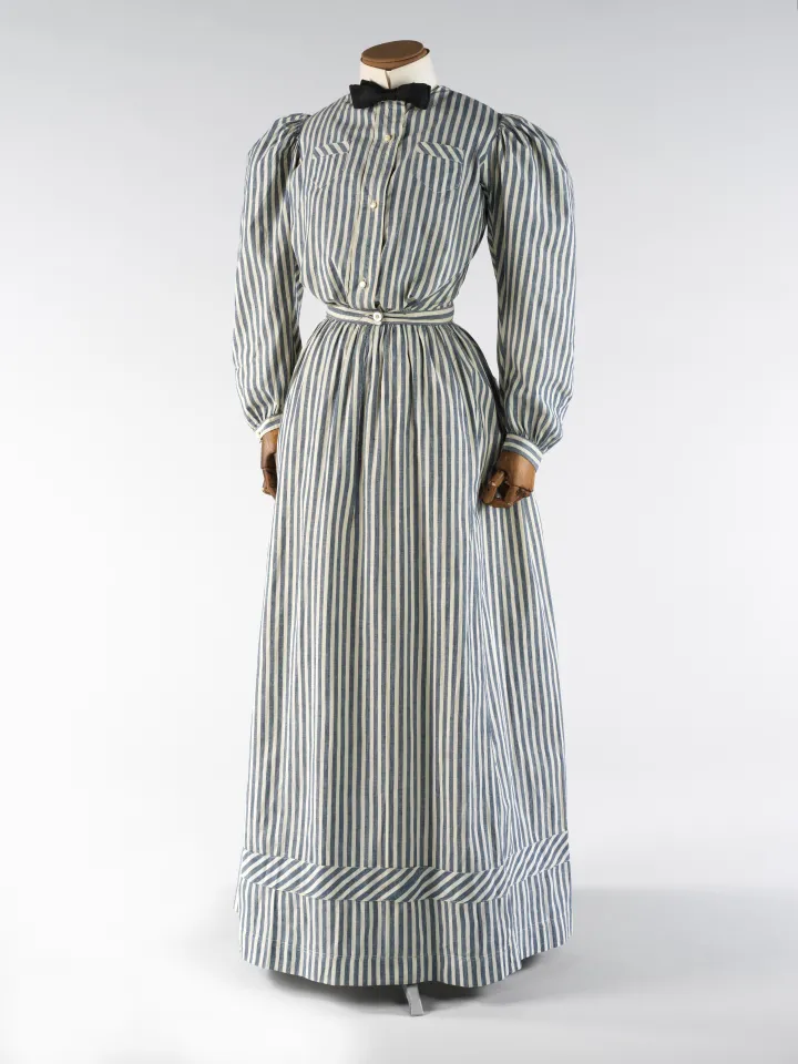 A long-sleeved, floor-length, grey and white striped dress.