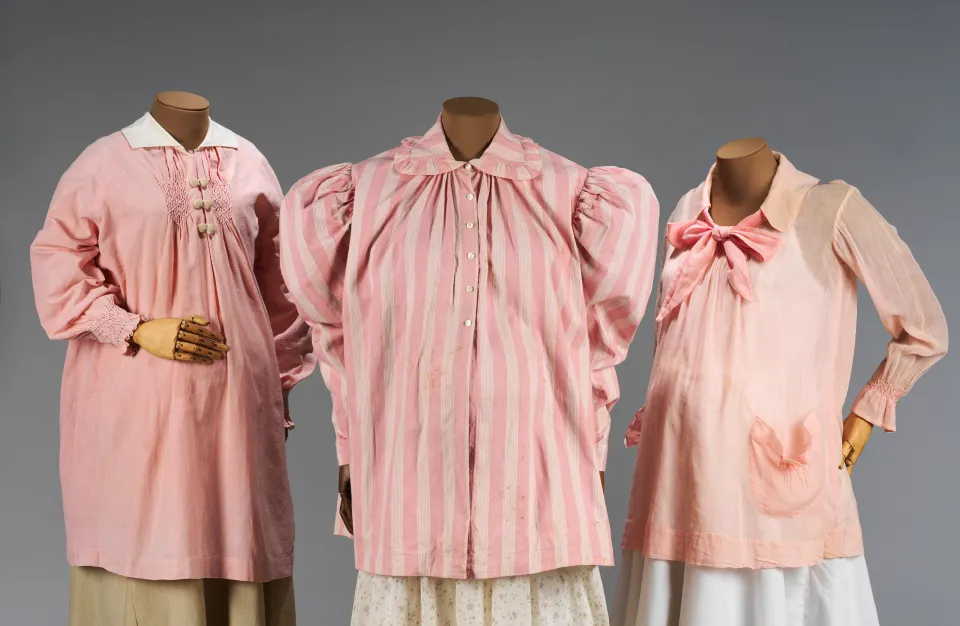 Three pink, long-sleeved maternity shirts.