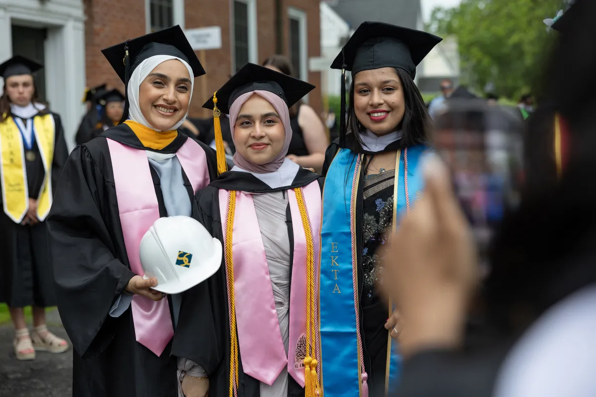 A group of seniors in caps and gowns smile on Commencement Day