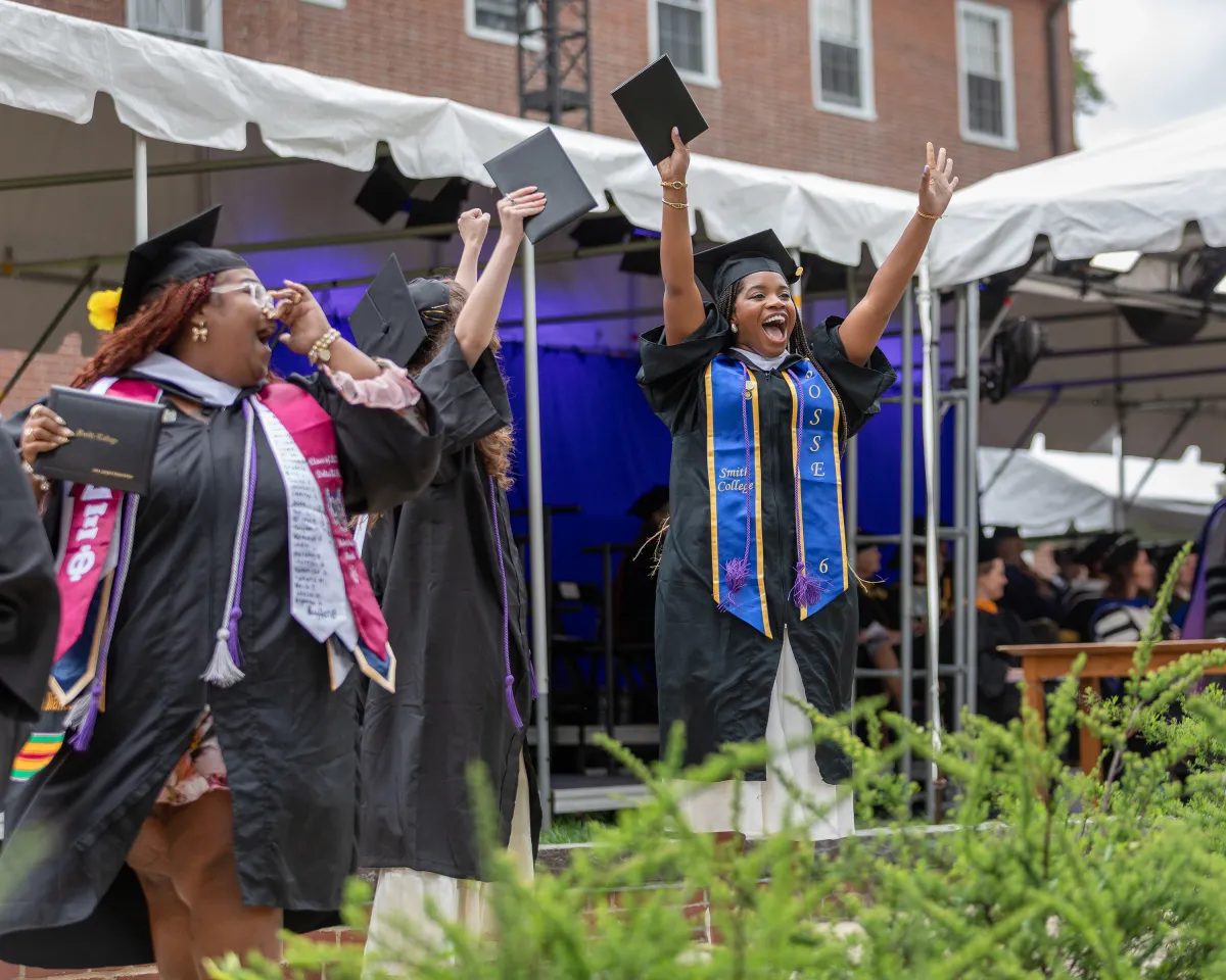 A senior cheers at the crowd after walking across the stage during Commencement