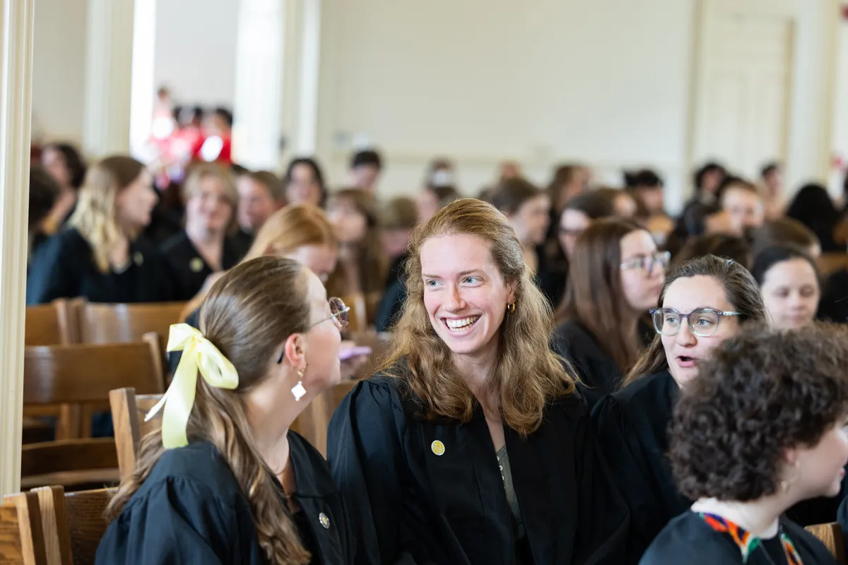 Two seniors laugh in the Chapel during Baccalaureate