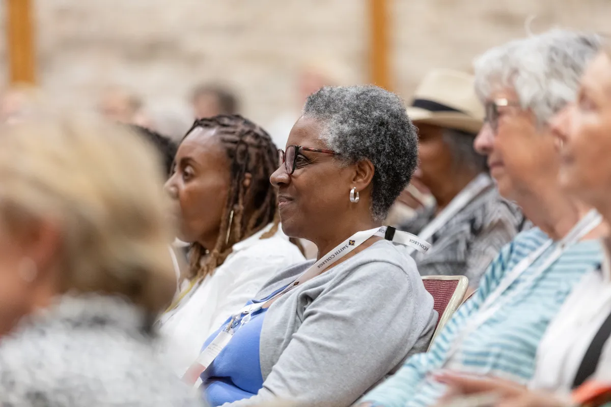 An alum smiles while listening to a panel discussion during Reunion