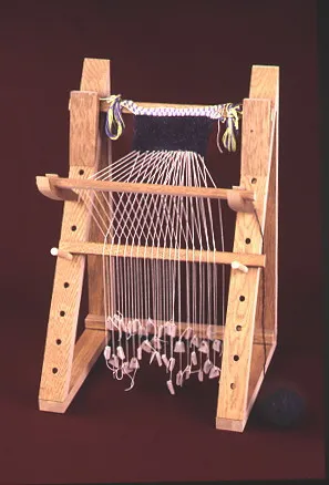 Small wooden loom with strings and fabric being woven
