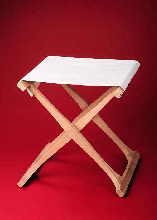A wooden folding stool with a white cloth seat and legs that form an "X" shape