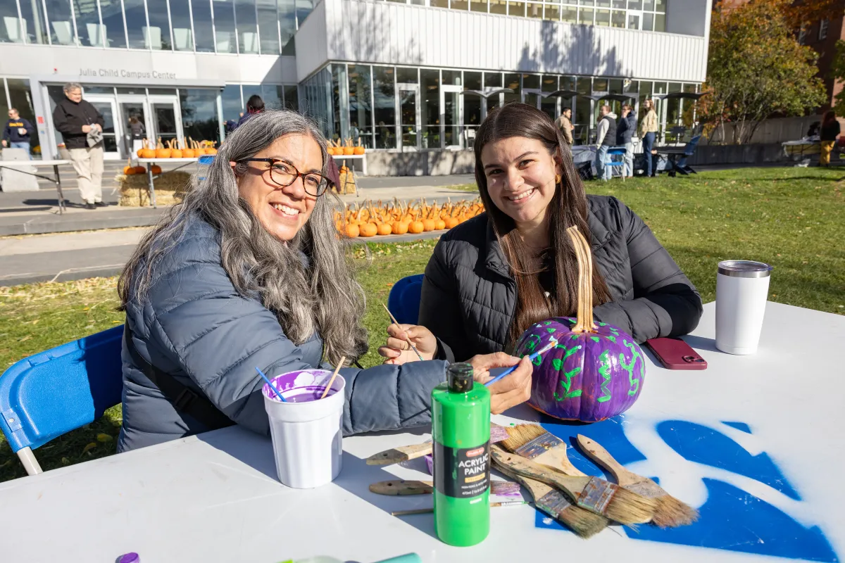 A Smithie and a family member paint a pumpkin on Chapin lawn during Family Weekend.