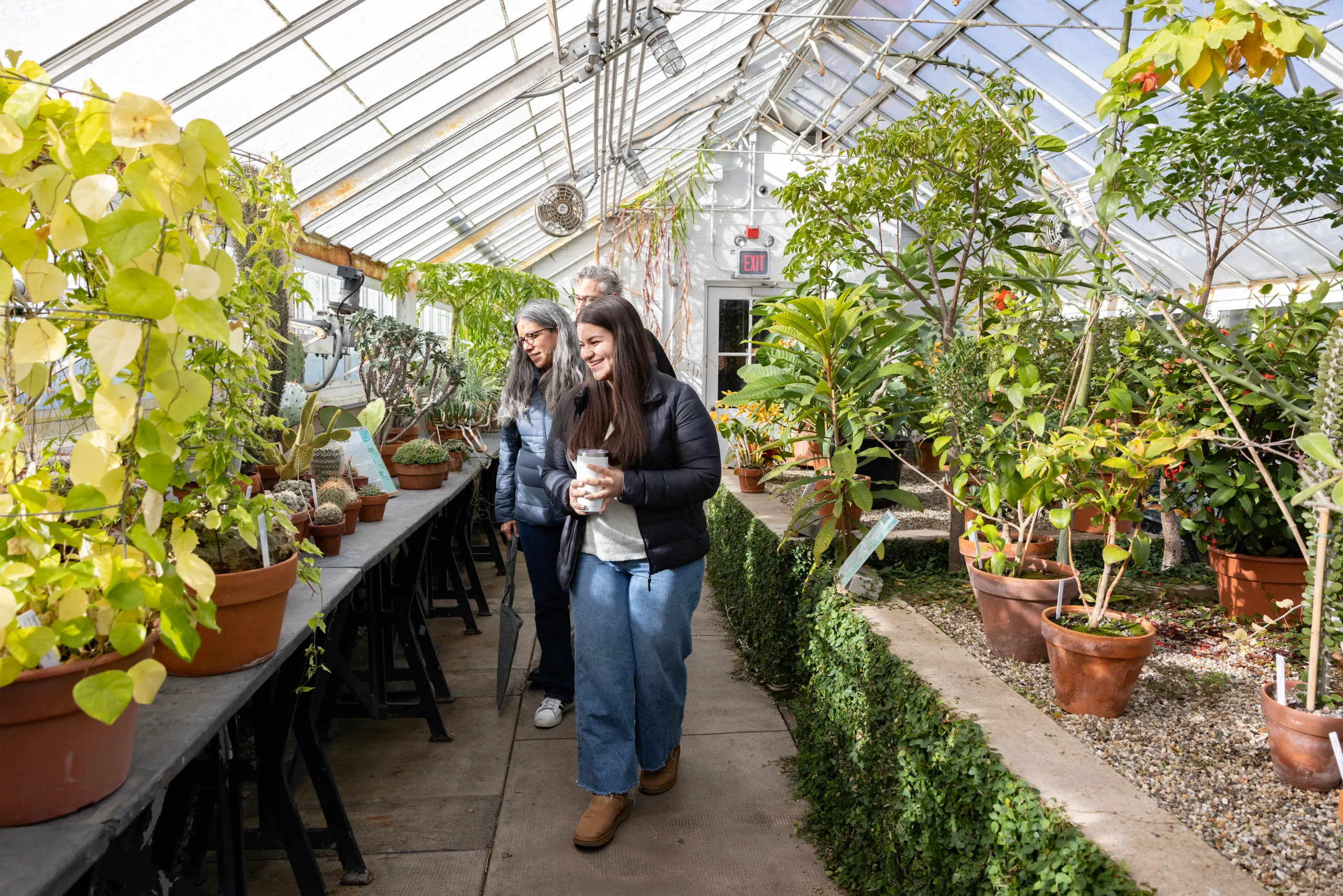 A student and parents walk through the greenhouses