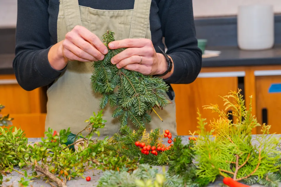 Julie Thomson's hands as she makes an evergreen bundle