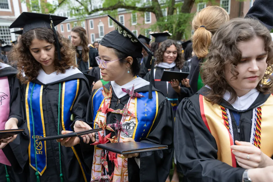 Graduates pass diplomas around the Diploma Circle in 2025