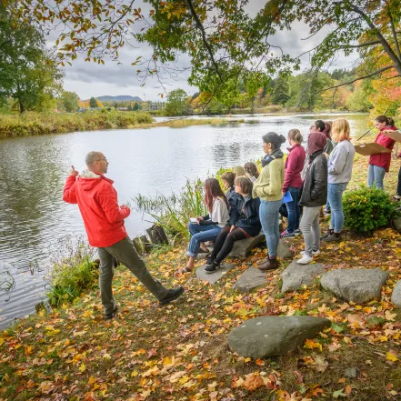 Students listening to a lecture near the Mill River.