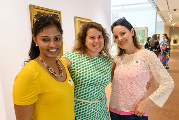 Three alumnae standing close together and smiling in the Smith College Museum of Art